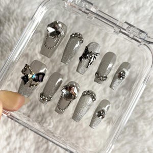 Puede incluir: Una taza de cerámica blanca con un asa negra y el texto "But First, Coffee" en un estilo manuscrito. La taza está sobre una superficie blanca. La taza es probablemente para bebidas calientes.