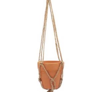 May include: A hanging terracotta planter with a natural jute macrame hanger. The planter is suspended from a metal ring and features a knotted design around the pot. The jute rope is a light brown color.