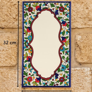 May include: Rectangular ceramic wall art, 12.6 inches tall and 6.7 inches wide, with a cream-colored center and a floral border. The border features red, blue, and green flowers and leaves on a white background, framed by a dark blue edge.