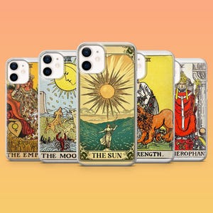 May include: A selection of clear phone cases showcasing tarot card artwork. The cases feature colourful illustrations of The Empress, The Moon, The Sun, Strength, and The Hierophant. Each case has a unique design with vivid colours and detailed imagery.