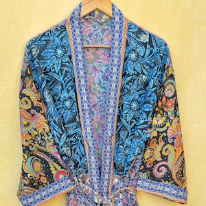 May include: A long, flowing robe with a vibrant floral and paisley pattern in shades of blue, black, and orange. The robe is made of a lightweight fabric and features a matching belt. The robe is approximately 55 inches long.