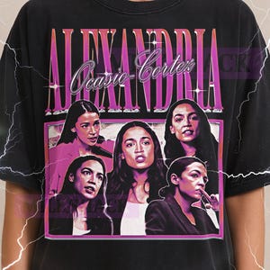 May include: Black unisex t-shirt featuring a graphic of Alexandria Ocasio-Cortez with the text "ALEXANDRIA Ocasio-Cortez" in a retro style. The shirt has a distressed look and a Milkshake logo on the top left.