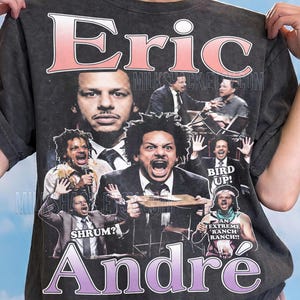 May include: A charcoal gray short-sleeve t-shirt featuring a collage of Eric André in various poses and outfits. The shirt displays the text "Eric" at the top, "André" at the bottom, and "BIRD UP!", "SHRUM?", and "AN EXTREME RANCH RANCH!!" in the graphic.