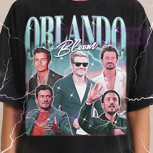Könnte beinhalten: Schwarzes T-Shirt mit einem Retro-Grafik von Orlando Bloom und dem Text "ORLANDO Bloom". Das Design hat einen Vintage-Look mit Blitz-Akzenten, ideal für Fans.