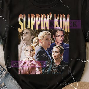 Peut inclure: T-shirt noir avec un graphisme représentant une femme dans différentes poses, et le texte "SLIPPIN' KIM" en or et violet. Le design a une esthétique vintage, avec des éclairs.