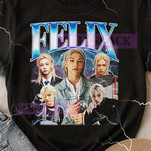 May include: Black t-shirt featuring a graphic of the name "FELIX" in blue and white, with a vintage design. The graphic includes images of five people. The shirt is a crew neck style.