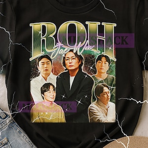 May include: Black t-shirt featuring a graphic design with the text "ROH Jae-Won" in a vintage style. The design includes a group of five people. The shirt has a crew neck and short sleeves.