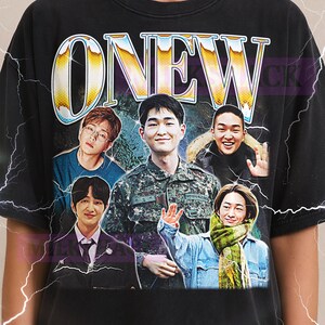 Puede incluir: Camiseta unisex negra con la palabra "ONEW" en un estilo vintage y un grupo de cinco personas. La camiseta incluye el texto "MILKSHACK" en la parte superior. La parte inferior de la camiseta tiene texto sobre el tallaje.