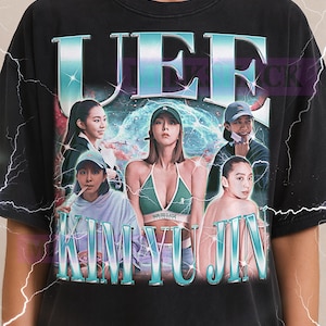 May include: Black unisex t-shirt featuring the text "UEF KIM YU JIN" in a teal, outlined font. The shirt displays a graphic of several people. The Milkshake logo is at the top.