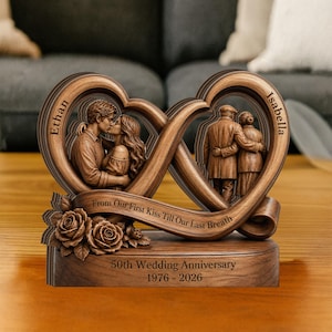 May include: A wooden anniversary sculpture featuring two intertwined hearts with carved images of a couple kissing and an elderly couple embracing. The base reads "50th Wedding Anniversary 1976-2026" with the text "From Our First Kiss Till Our Last Breath".