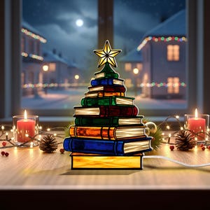 May include: A Christmas tree-shaped lamp made of stacked books with a gold star on top. The books are various colors, including blue, green, and orange. The lamp is on a wooden surface with candles and pinecones.