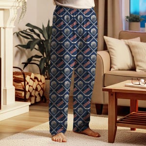 May include: Navy blue pajama pants with a repeating pattern of hockey helmets, crossed hockey sticks, and the word "NAME" in a diamond grid. The pants are made of a soft fabric.