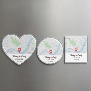 May include: Three clear acrylic magnets with map designs. One is heart-shaped, one is round, and one is rectangular. Each features a red pin, the names "Tommy & Emily", and the word "ENGAGED" with a date.