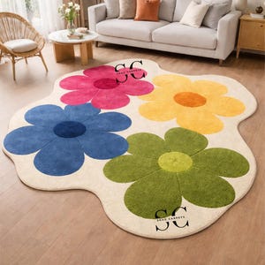 May include: A large, flower-shaped rug with four colorful blooms: pink, blue, yellow, and green. The rug has a cream-colored background and is placed on a hardwood floor. The rug is a decorative home decor item.