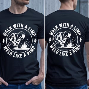 May include: Black t-shirt with a white graphic featuring a welder inside a circle with the text "WALK WITH A LIMP WELD LIKE A PIMP" and lightning bolts. The design is on the front and back.
