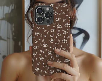 Könnte beinhalten: Eine braune Handyhülle mit einem weißen Blumenmuster. Die Hülle hat ein sich wiederholendes Design aus kleinen weißen Blumen und Blättern. Die Handyhülle ist für ein Smartphone konzipiert.