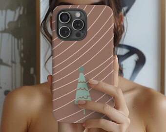 May include: A phone case with a brown background and diagonal white stripes. A light green Christmas tree design is centered on the case. The case has a camera cutout and is held by a person.