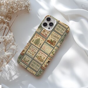May include: A phone case with a festive Christmas design. The case features a collage of vintage-style postage stamps with holiday-themed illustrations and text, including "Christmas Trees for Sale" and "Santa's Workshop". The color palette includes green, beige, and red.