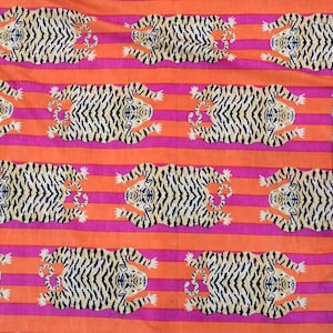 May include: A patterned fabric featuring a repeating design of tigers. The tigers are cream with black stripes, set against a backdrop of orange and pink horizontal stripes.