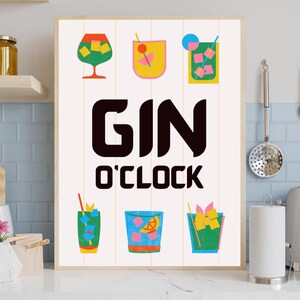 May include: A framed print featuring the words "GIN O'CLOCK" in bold black letters. The print showcases six colorful illustrations of cocktails, each with different garnishes and ice. The background is a light cream color.