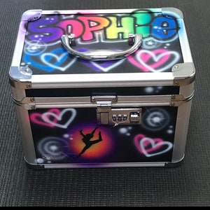 May include: A black aluminum case with a combination lock. The case is decorated with a colorful graffiti design, including the name "Sophie" and hearts. A silhouette of a dancer is on the bottom of the case.