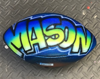 May include: A blue and green football with the name "MASON" painted on it in a graffiti style.