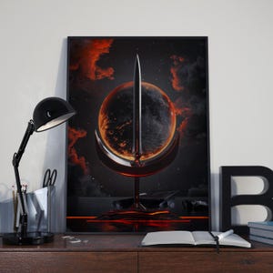 May include: A framed art print featuring a surreal, fantasy scene. A large, fiery orb is bisected by a sword, set against a dark, starry sky with red and black clouds. The artwork is displayed on a wooden desk with a black desk lamp.