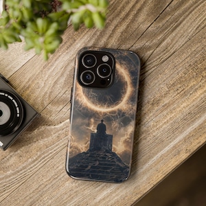 May include: A black smartphone case featuring a surreal image of a figure seated on a stone structure, with a glowing ring in the background. The case has a glossy finish and a camera cutout.