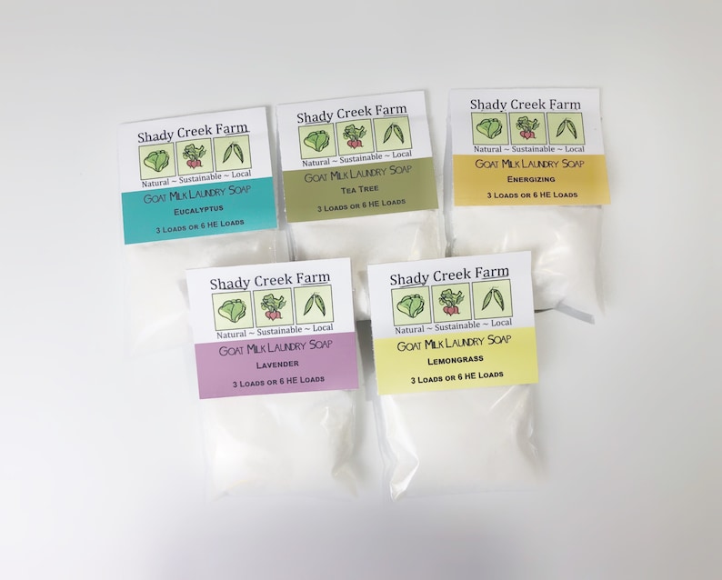 Peut inclure: Cinq petits sachets blancs de savon &agrave; lessive au lait de ch&egrave;vre avec des &eacute;tiquettes indiquant "Shady Creek Farm" et listant diff&eacute;rents parfums : Eucalyptus, Tea Tree, &Eacute;nergisant, Lavande et Citronnelle. Chaque sachet est &eacute;tiquet&eacute; "Naturel - Durable - Local" et indique le nombre de brass&eacute;es que le savon fera.