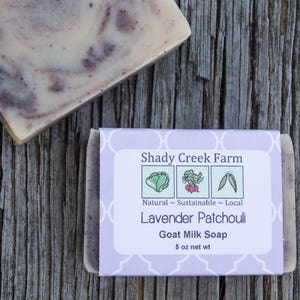 May include: A bar of lavender patchouli goat milk soap in a purple and white box with the text "Shady Creek Farm", "Natural - Sustainable - Local", "Lavender Patchouli", "Goat Milk Soap", and "5 oz net wt".