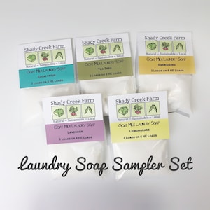 Peut inclure: Un ensemble de cinq petits sachets blancs contenant du savon &agrave; lessive au lait de ch&egrave;vre. Chaque sachet porte une &eacute;tiquette avec un logo vert et le texte "Shady Creek Farm" et "Savon &agrave; lessive au lait de ch&egrave;vre" avec un parfum diff&eacute;rent indiqu&eacute; en dessous. Les parfums sont Eucalyptus, Tea Tree, &Eacute;nergisant, Lavande et Citronnelle. Le texte "Ensemble d'&eacute;chantillons de savon &agrave; lessive" est &eacute;crit sous les sachets.