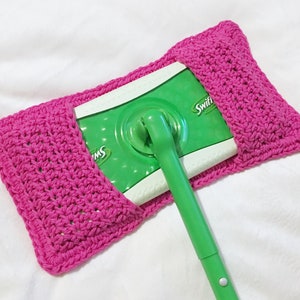May include: A pink crocheted holder for a Swiffer wet jet mop refill. The holder is made with a simple stitch pattern and has a flap that folds over to secure the refill.