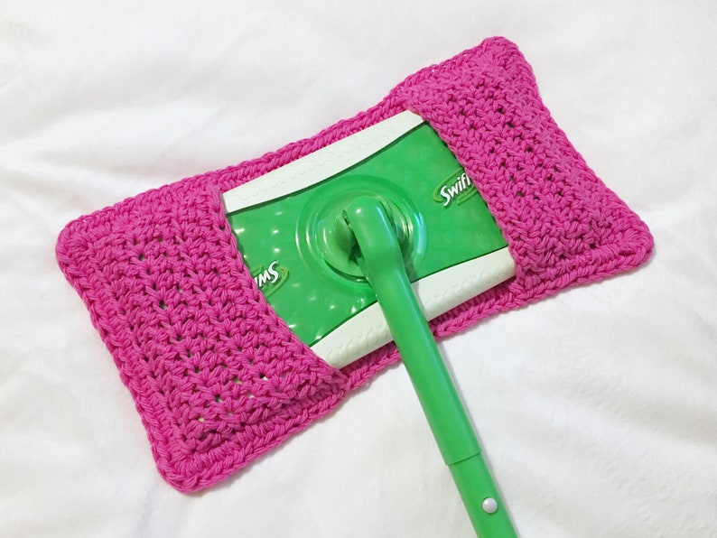 May include: A pink crocheted holder for a Swiffer wet jet mop refill. The holder is made with a simple stitch pattern and has a flap that folds over to secure the refill.