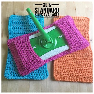 May include: Three crocheted mop head covers in pink, turquoise, and orange. The covers are made with a simple stitch pattern and are designed to fit standard and XL size mop heads. The text "XL & STANDARD SIZES AVAILABLE" is visible in the image.