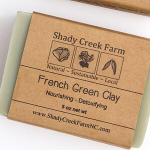 May include: A bar of French Green Clay soap from Shady Creek Farm, wrapped in brown paper. The label includes the text "Natural - Sustainable - Local" and "Nourishing - Detoxifying". The soap weighs 5 oz.