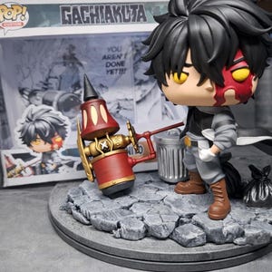Könnte beinhalten: Eine benutzerdefinierte Funko Pop-Figur eines Charakters mit schwarzen Haaren und rotem Gesicht, der ein rot-goldenes Objekt hält. Die Figur steht auf einem grauen Steinsockel, mit einem Mülleimer und einem schwarzen Sack. Die Box sagt "Gachikuta".