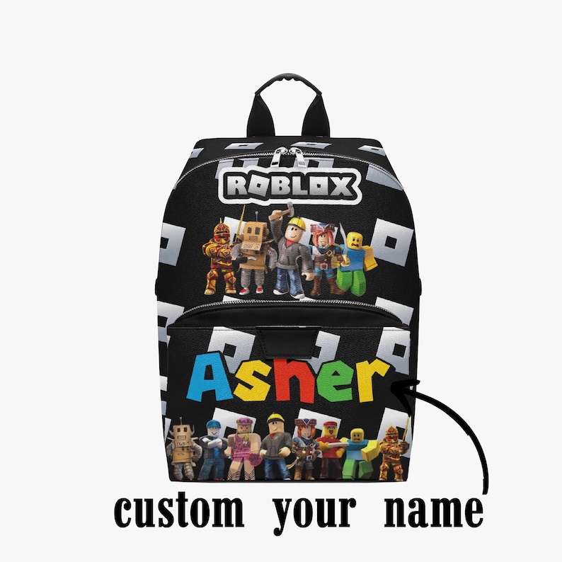May include: Black backpack featuring the Roblox logo and characters, with the name "Asher" in colorful letters. The backpack has a black background with white square patterns and the text "custom your name".