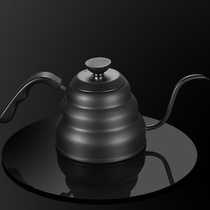 May include: A black gooseneck kettle with a curved spout and a wooden handle. The kettle has a rounded body with horizontal ridges and a small, round lid. Designed for pour-over coffee brewing, it sits on a reflective surface.