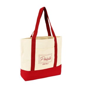 May include: Cream-colored tote bag with red accents. The bag features red handles and a red bottom panel. A rectangular logo with the word "Passih" is printed on the front. The bag has a pocket on the front.