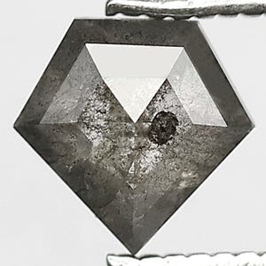 Può includere: Un diamante grigio scuro sfaccettato, tenuto da una pinzetta d'argento. Il diamante ha una forma geometrica unica con una parte superiore piatta e un'inclusione visibile. La pietra è posta su uno sfondo bianco.