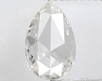 May include: A pear-shaped, faceted diamond held by tweezers. The colorless gemstone has a complex, geometric cut, reflecting light. The diamond is set against a plain white background.