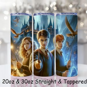 May include: Three stainless steel tumblers with a fantasy illustration featuring three characters, a castle, and flying birds. The tumblers have a blue and purple background with the text "20oz & 30oz Straight & Tapered".