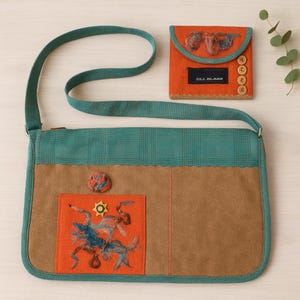 May include: A handmade shoulder bag with a brown suede body, teal plaid top, and teal trim. An orange square with an embroidered design is on the front. A matching orange glasses case with the text "DLL GLASS" and wooden buttons is also shown.