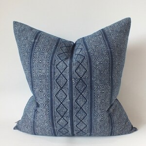 May include: A blue and white patterned cushion with a geometric design. The cushion is made of a soft, woven fabric.