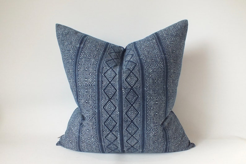 May include: A blue and white patterned cushion with a geometric design. The cushion is made of a soft, woven fabric.