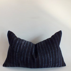 May include: A dark blue striped pillow with a subtle sheen. The pillow is rectangular and has a simple design.