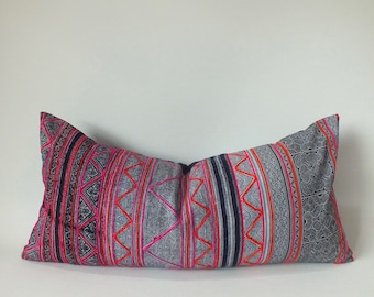 May include: Rectangular decorative pillow with a gray background and a vibrant pattern in pink, red, and black. The pillow features geometric and floral designs, creating a striking visual contrast. The pillow is a decorative home accent.