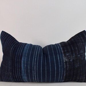 May include: A long, rectangular pillow with a blue and white striped pattern. The pillow is made of a soft, textured fabric.