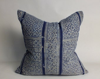 May include: Square throw pillow with a blue and white geometric pattern. The pillow features a repeating design of small squares and rectangles, with vertical stripes of solid blue. The pillow is a soft, decorative item.