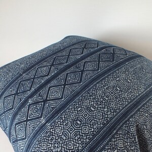 May include: A blue and white patterned cushion cover with a geometric design. The cushion cover is made of a soft, woven fabric.